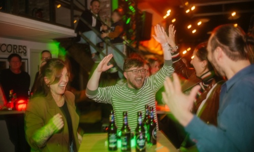 Mehrere Personen stehen jubelnd um einen Stehtisch